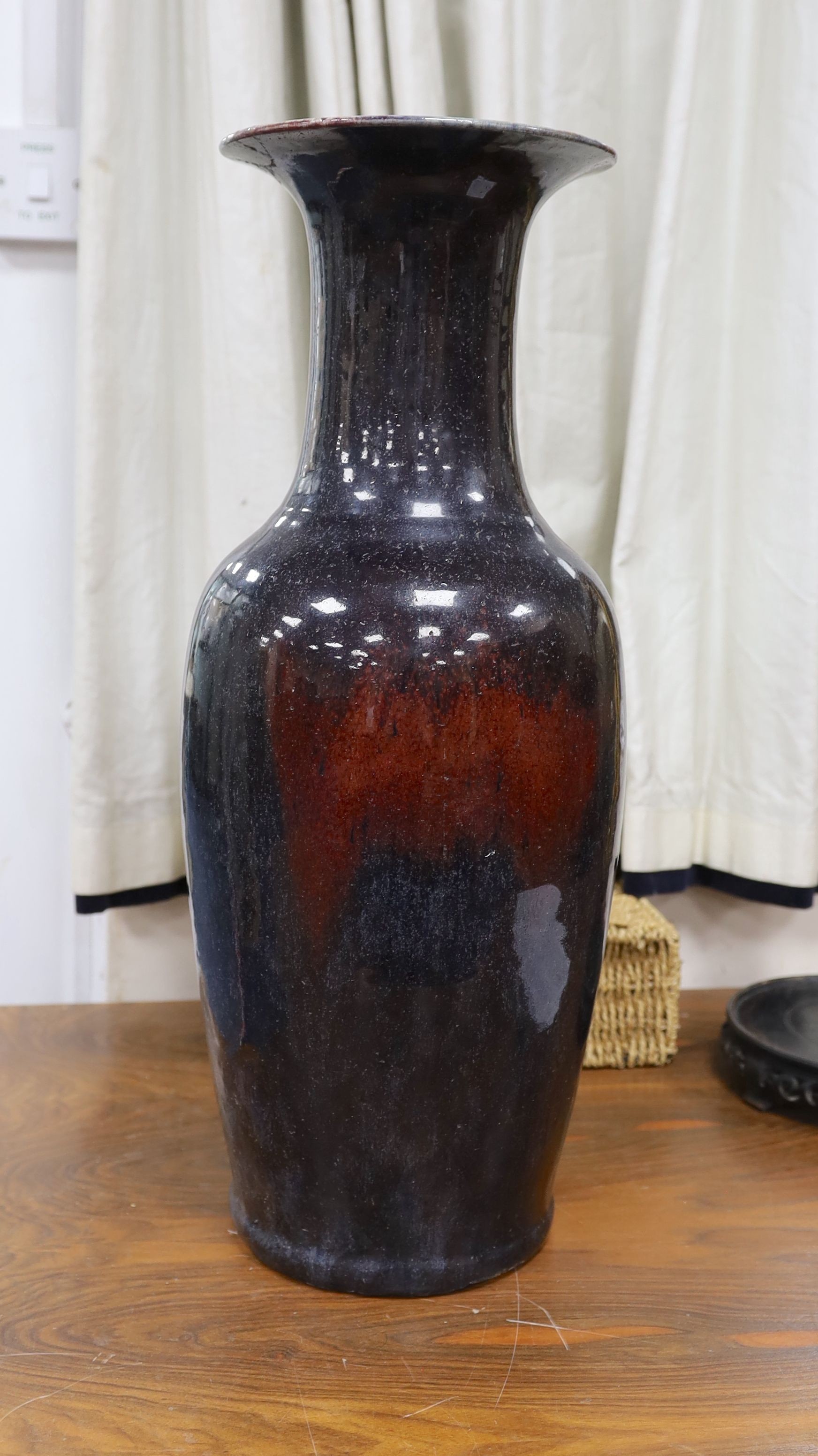 A large Chinese sang de boeuf glazed vase on carved wooden stand., Vase 61 cms high not including stand.